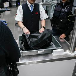 Zwei Beamte der Bundespolizei schauen sich in der Sicherheitskontrolle eines Flughafens ein verdächtiges Gepäckstück an.