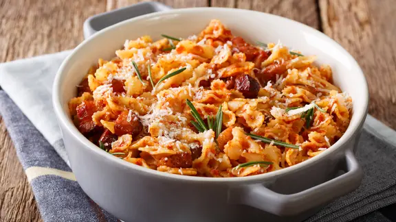 Ein Pastagericht, garniert mit Rosmarinnadeln, in einem Topf.