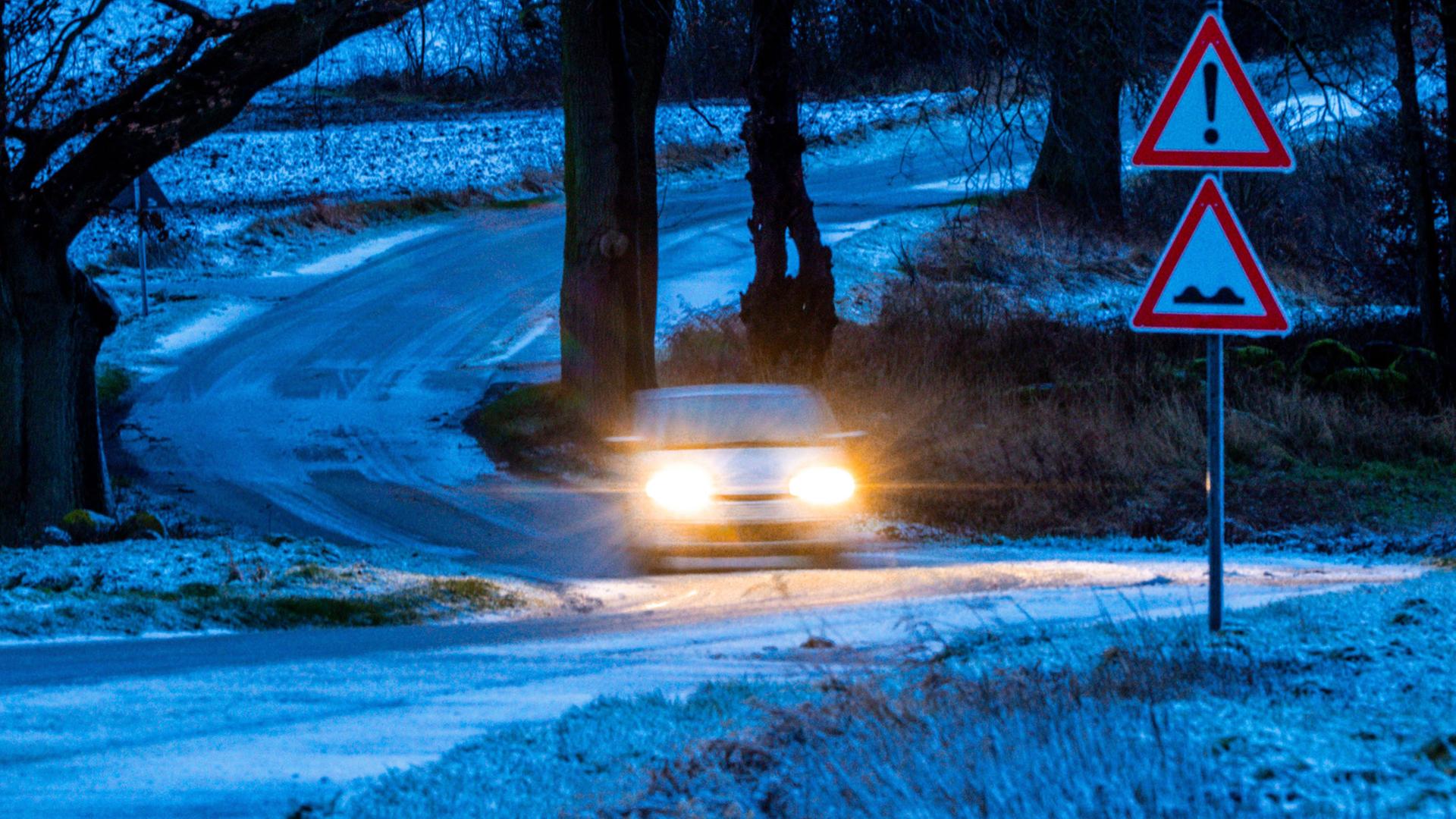 Ein Auto fährt im Dunkeln über eine verschneite Straße. |  Jens Büttner/dpa +++ dpa-Bildfunk +++