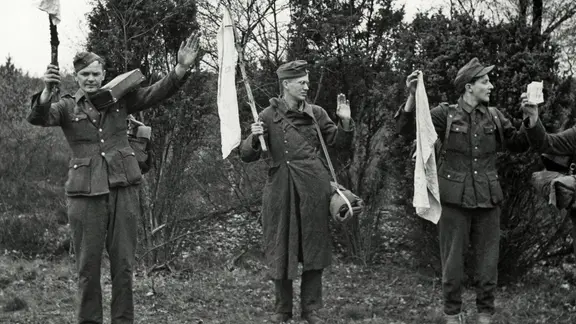 Wehrmachtssoldaten ergeben sich 1945 und halten weiße Tücher hoch.