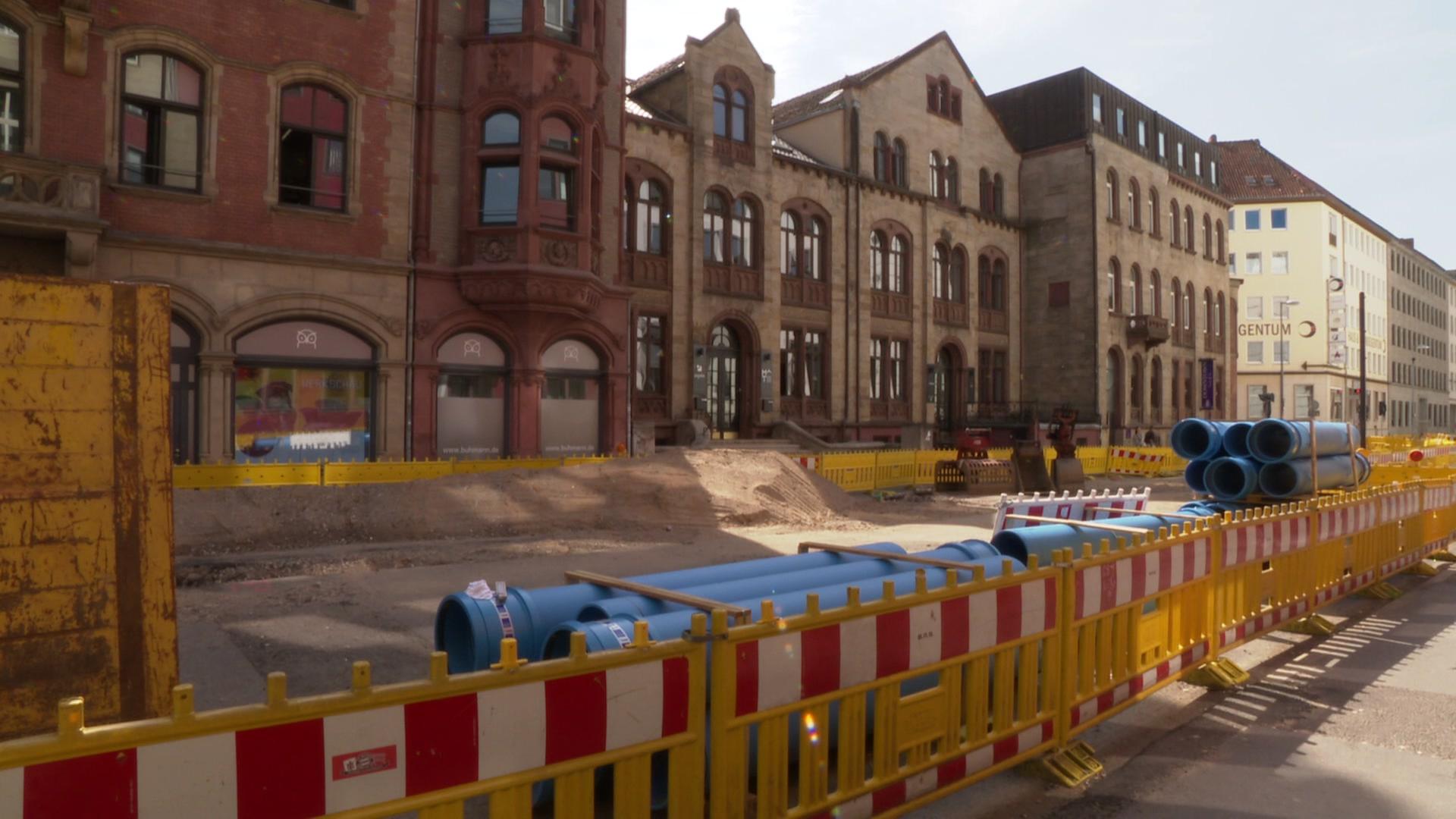 Blaue Rohre liegen auf einer Baustelle hinter einer gelb-roten Absperrung. | Kristin Häfemeier, NDR