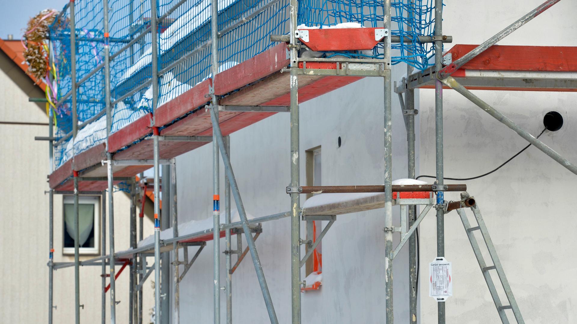 Ein Baugerüst an einer Baustelle für ein Einfamilienhaus ist schneebedeckt. | picture alliance/dpa/dpa-Zentralbild | Volkmar Heinz