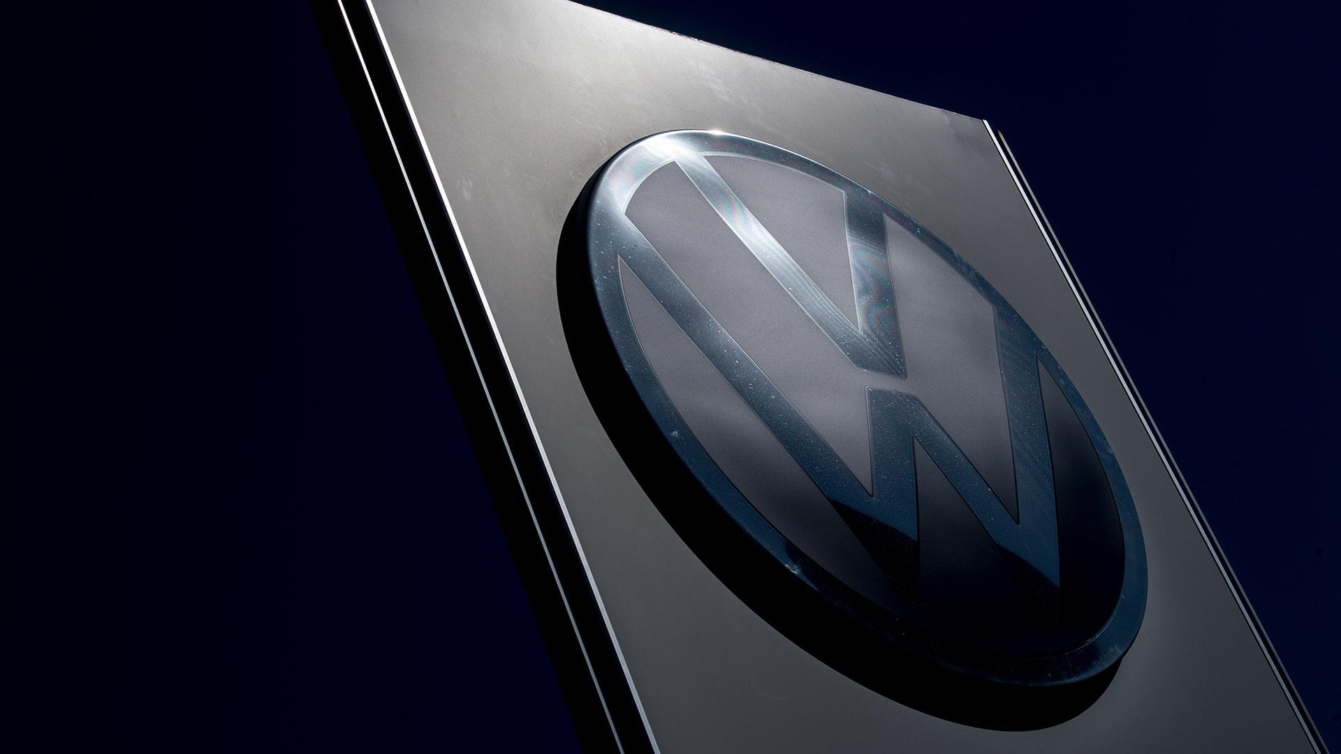 Ein großes VW-Logo steht an der Einfahrt zum Fahrzeugwerk von Volkswagen. | picture alliance/dpa/Hendrik Schmidt, Hendrik Schmidt