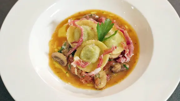 Ravioli mit Champignons, Tomate und Petersilie auf einem Teller serviert