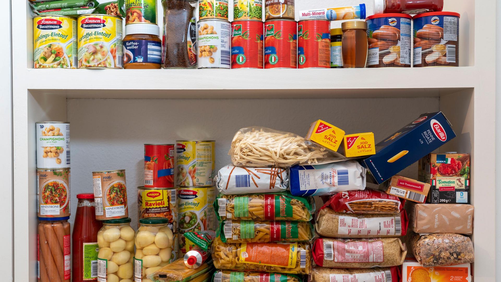 Ein Regal mit haltbaren Lebensmitteln wie Nudeln und Gemüsekonserven. | picture-alliance, Jochen Tack