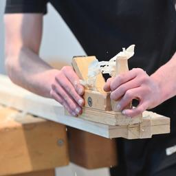 Ein Auszubildender schleift Holz ab.