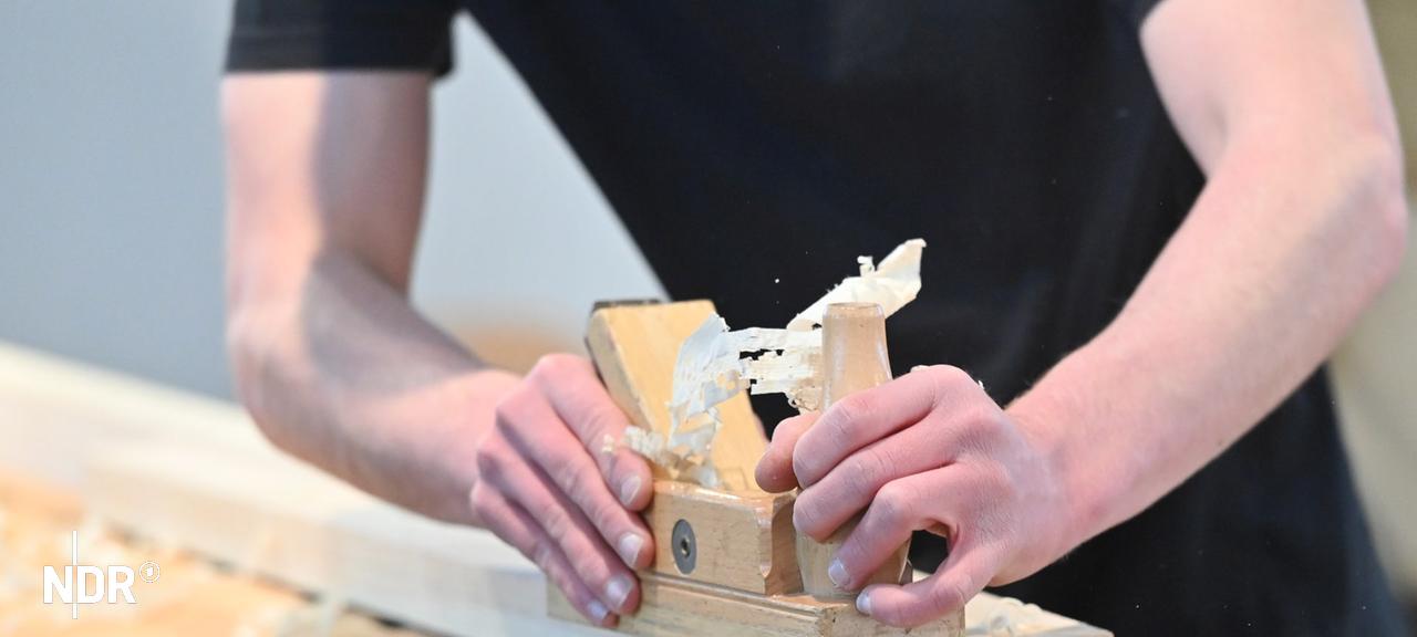 Ein Auszubildender schleift Holz ab. | picture alliance / SvenSimon Ein Auszubildender schleift Holz ab.