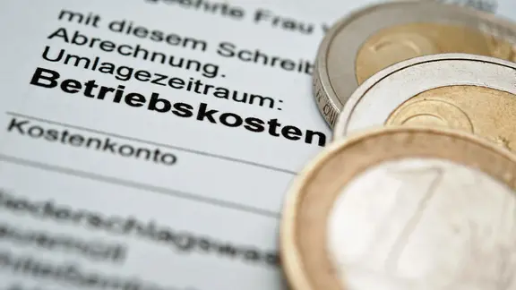 Münzen liegen auf einer Betriebskostenabrechnung für eine Mietwohnung.