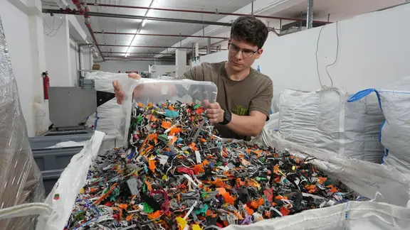 Mann füllt Plastikreste in Karton.