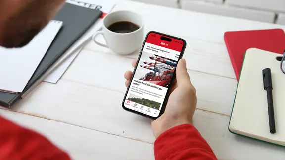 Eine Hand Hält ein Smartphone mit der NDR Hamburg App.