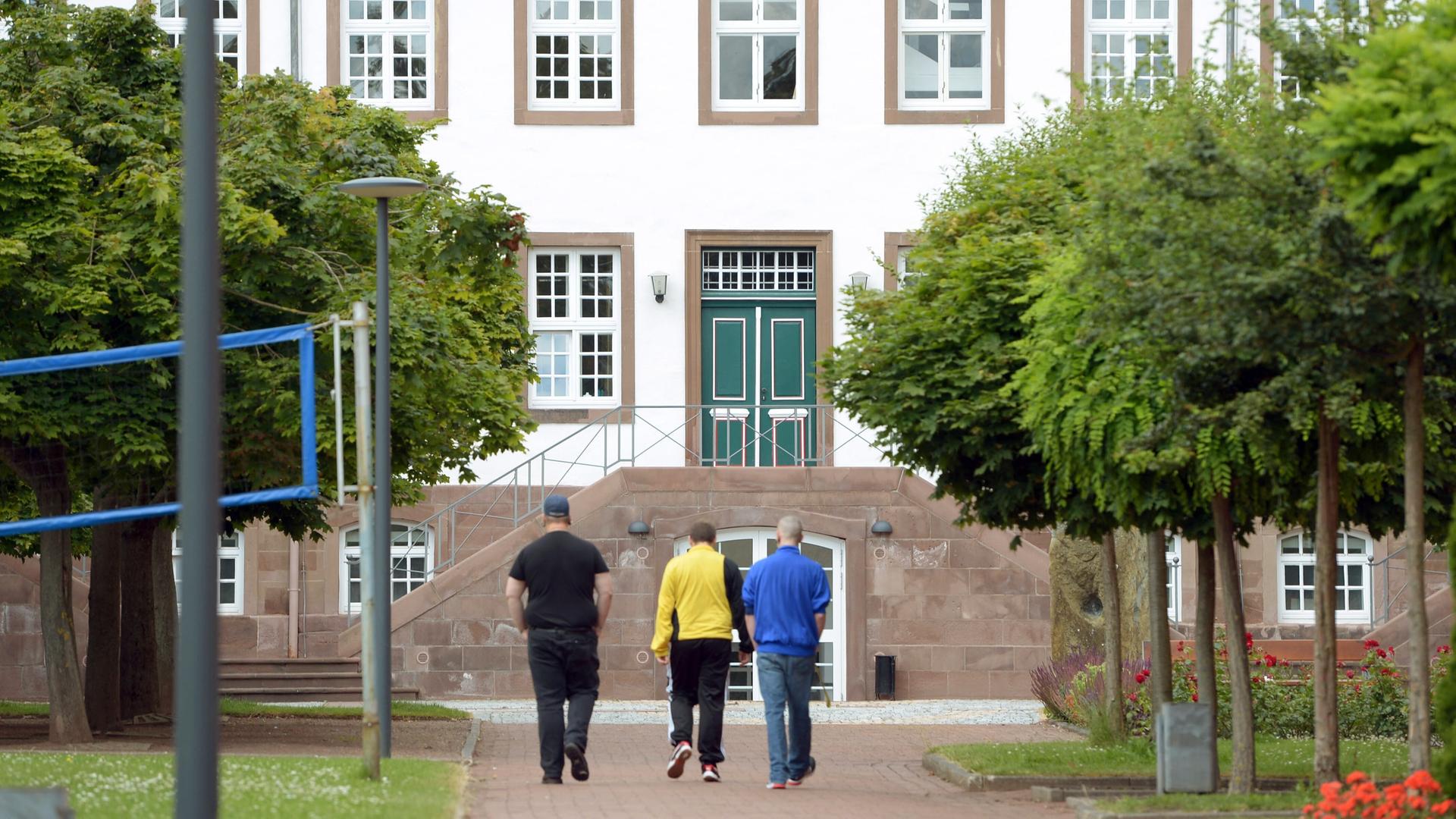 Drei Männer laufen auf den Eingang eines Gebäudes zu.  | picture alliance / dpa | Peter Steffen