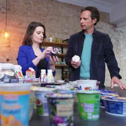 Jo Hiller und Verbraucherschützerin Britta Schautz im Gespräch. Vor ihnen stehen mehrere Milchprodukte.