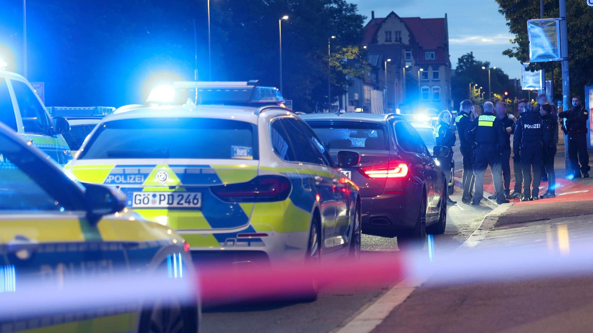 Polizisten und Polizeifahrzeuge stehen hinter einer Absperrung. | dpa, Stefan Rampfel