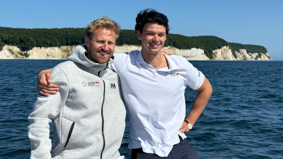 Das deutsche Sail-GP-Team besteht aus Teamkapitän und Steuermann Erik Heil (l.) sowie aus "Grinder" Jonathan Knottnerus-Meyer. | NDR, Moritz Schröder Zwei Segelsportler stehen nebeneinander und haben jeweils einen Arm über die Schultern des anderen gelegt.