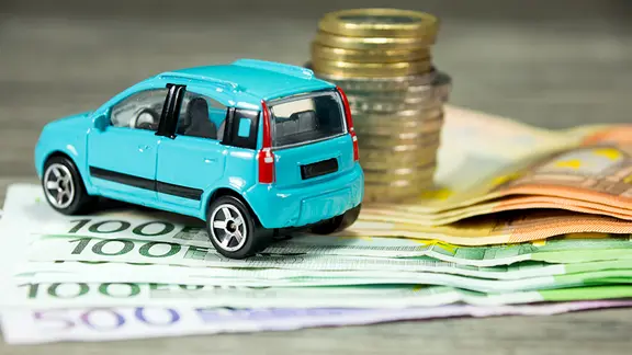 Ein Spielzeugauto steht auf Geldscheinen