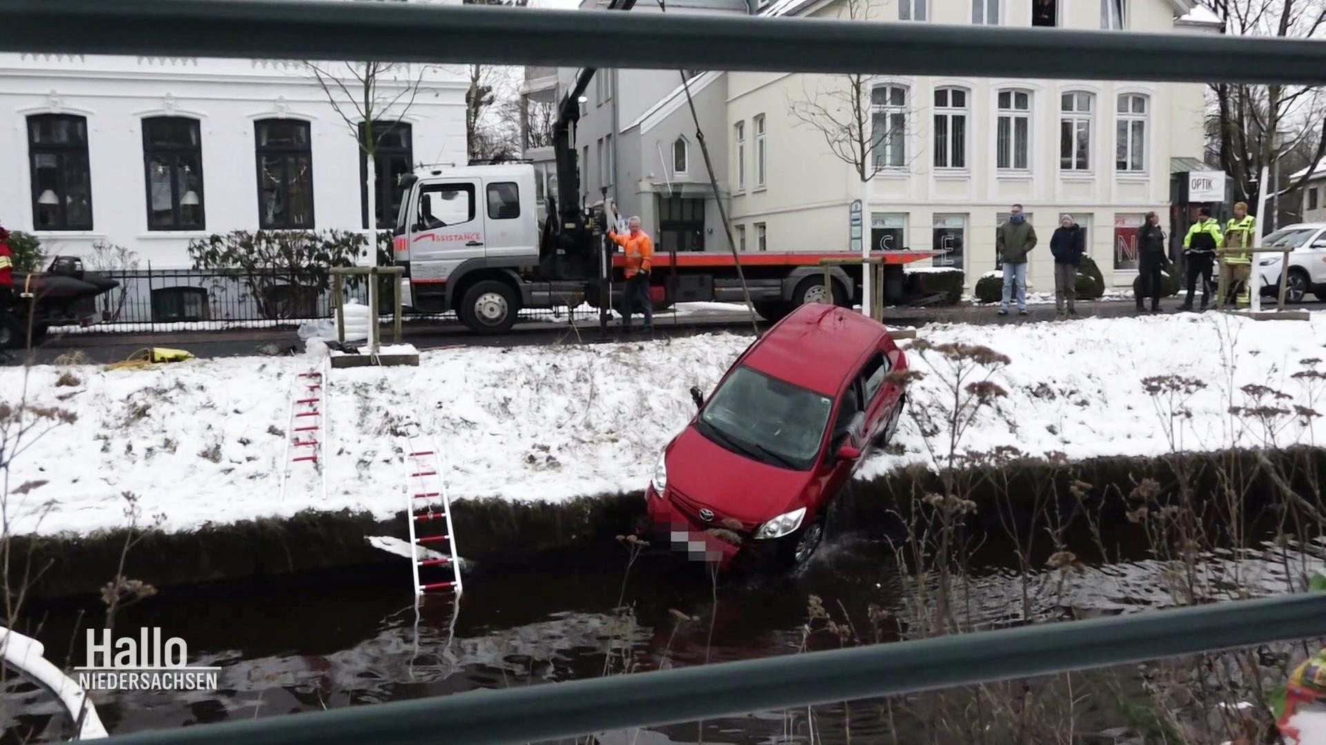 Mit einem Kranfahrzeug wird ein PKW aus einem Fluss gezogen. | Screenshot