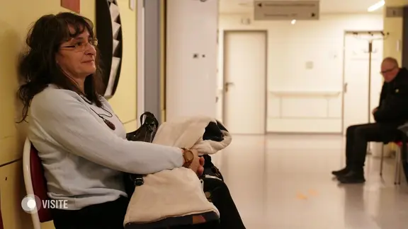 Eine Frau sitzt in einem Wartebereich.