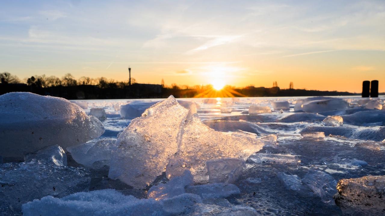 Die aufgehende Sonne beleuchtet Eisstücke auf dem zugefrorenen Maschsee. 