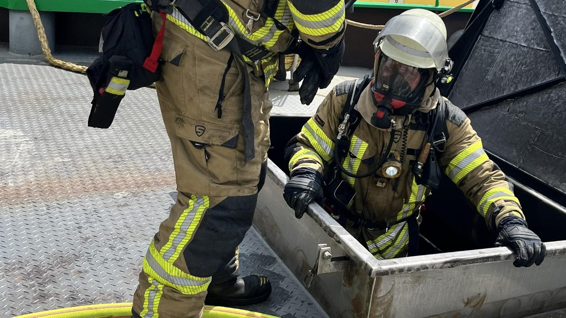 Feuerwehrleute klettern durch eine Luke in ein brennendes Schiff in Bremerhaven. | Feuerwehr Bremerhaven