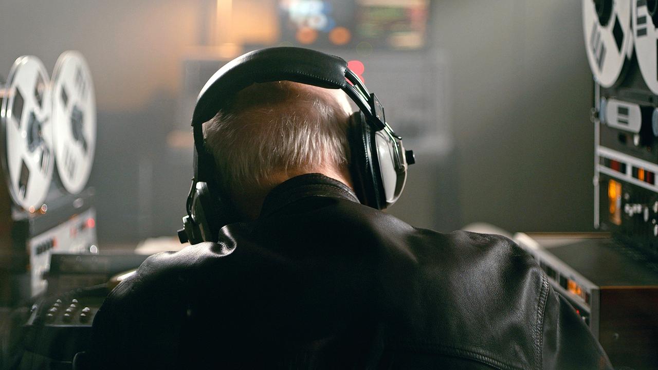 Ein Ermittler bei einer Abhör-Aktion mit Kopfhörern und Tonbandgeräten. Nachgestellte Szene aus der Dokumentation 