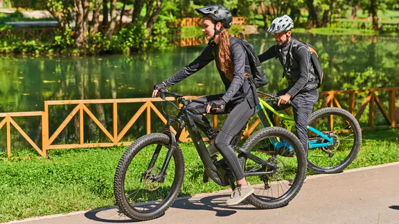 Zwei E-Bike-Fahrer fahren durch einen Park. | Imago Images, Zoonar, Benis Arapovic Zwei E-Bike-Fahrer fahren durch einen Park.