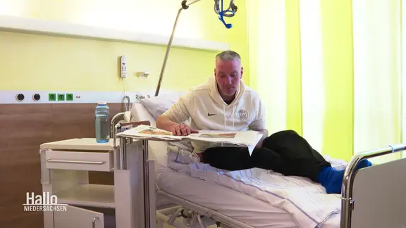 Jonny sitzt auf einem Krankenbett in einer Klinik, in der er zur Entgiftung ist.