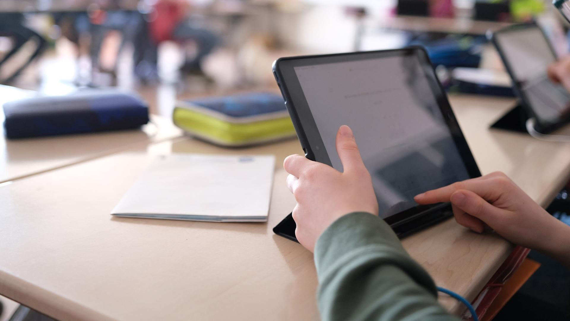 Ein Finger tippt auf einem Tablet, es steht in dem Klassenzimmer einer Schule. | picture alliance/dpa | Bernd Weißbrod