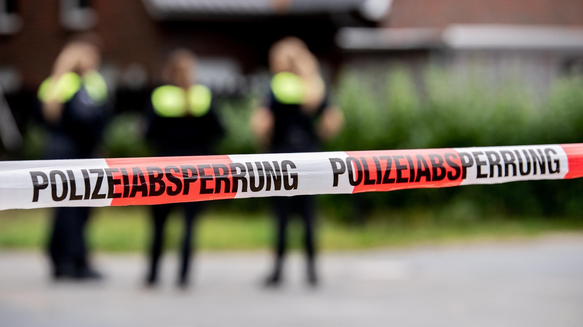 Ein rot-weiß gestreiftes Absperrband ist vor drei Polizistinnen aufgepspannt. | Hauke-Christian Dittrich, dpa