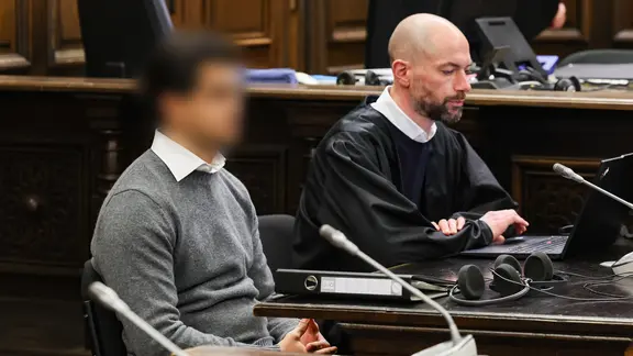Ein Mann wartet zusammen mit seinem Anwalt in einem Saal des Hamburger Landgerichtes auf den Beginn seines Prozesses wegen versuchten Totschlags. Der Angeklagte soll vor einem Hamburger Restaurant auf einen Mann mehrere Schüsse abgegeben haben.