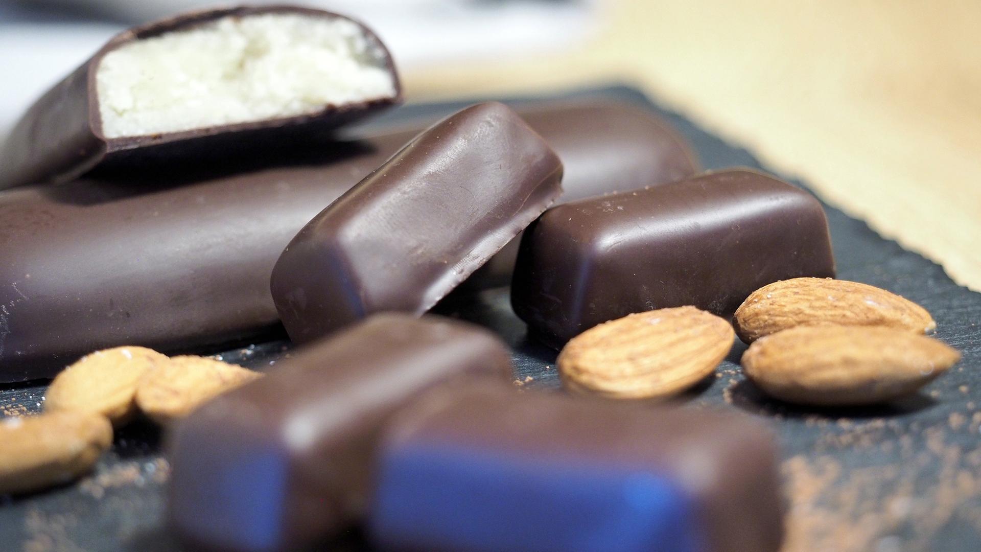 Mit dunkler Schokolade umhüllte Marzipanbrote in verschiedenen Größen liegen auf einem Brett. | NDR, Anja Deuble