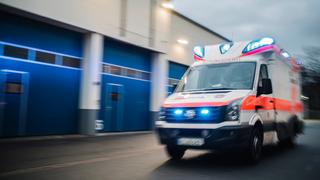 Ein Rettungswagen fährt mit Blaulicht über eine Straße.