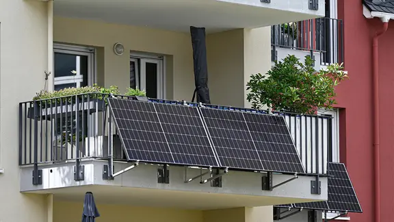 Balkonkraftwerk am Balkongelaender eines Mehrfamillienhauses.