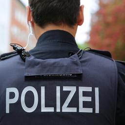 Schriftzug Polizei steht auf dem Rücken an der Uniform eines Polizisten.