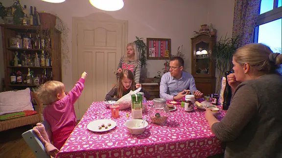 Eine Familie mit drei Kindern sitzt am Frühstückstisch.