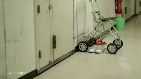 Ein Rollator steht auf einem Gefängnisflur.