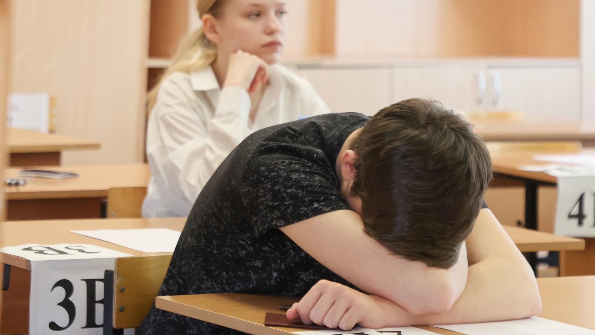 Ein Kind legt bei einer Prüfung in einer Schule den Kopf auf den Tisch. | picture alliance/globallookpress.com, Belkin Aleksey