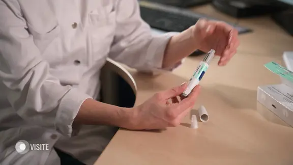 Eine Person im Arztkittel hält eine sogenannte Abnehmspritze in den Händen.