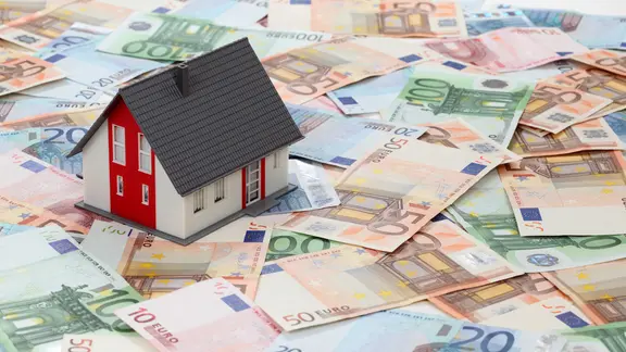 Ein Modellhaus steht auf Euroscheinen.