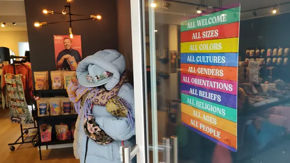 An der Tür eines Ladens hängt ein Plakat zum Thema Diversität.