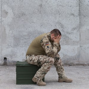 Ein traumatisierter Soldat verbirgt verzweifelt sein Gesicht in den Händen.