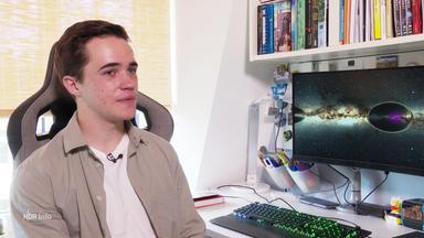 Schüler Mads Rabbel sitzt an einem Schreibtisch mit einem Bildschirm, auf dem ein Foto des Weltraums abgebildet ist.