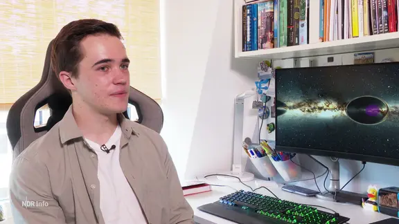 Schüler Mads Rabbel sitzt an einem Schreibtisch mit einem Bildschirm, auf dem ein Foto des Weltraums abgebildet ist.