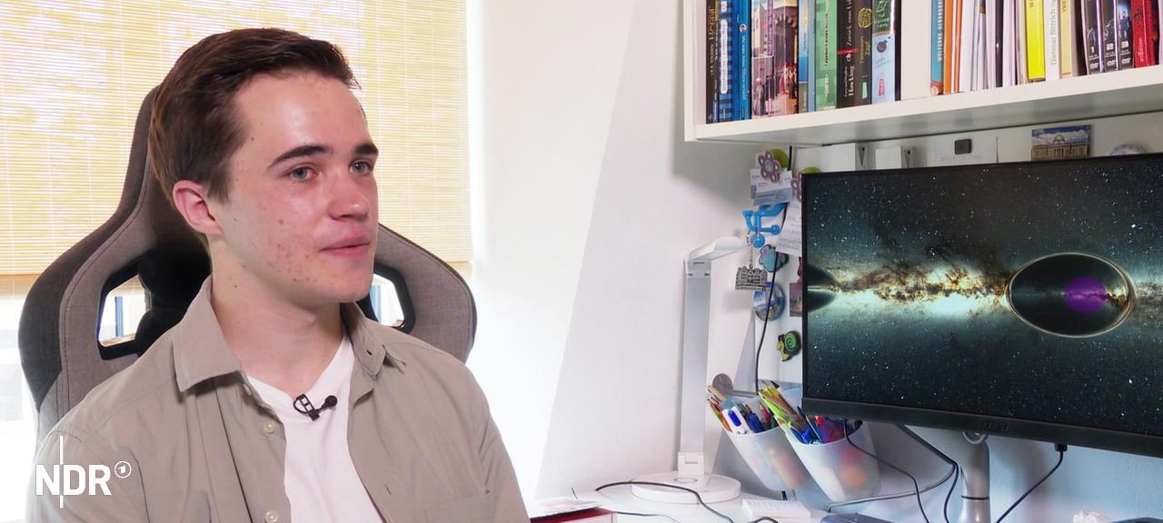 Schüler Mads Rabbel sitzt an einem Schreibtisch mit einem Bildschirm, auf dem ein Foto des Weltraums abgebildet ist. | Screenshot Schüler Mads Rabbel sitzt an einem Schreibtisch mit einem Bildschirm, auf dem ein Foto des Weltraums abgebildet ist.