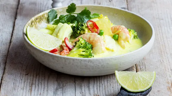 Eine Schüssel mit Curry-Kokos-Fischeintopf steht auf dem Tisch.