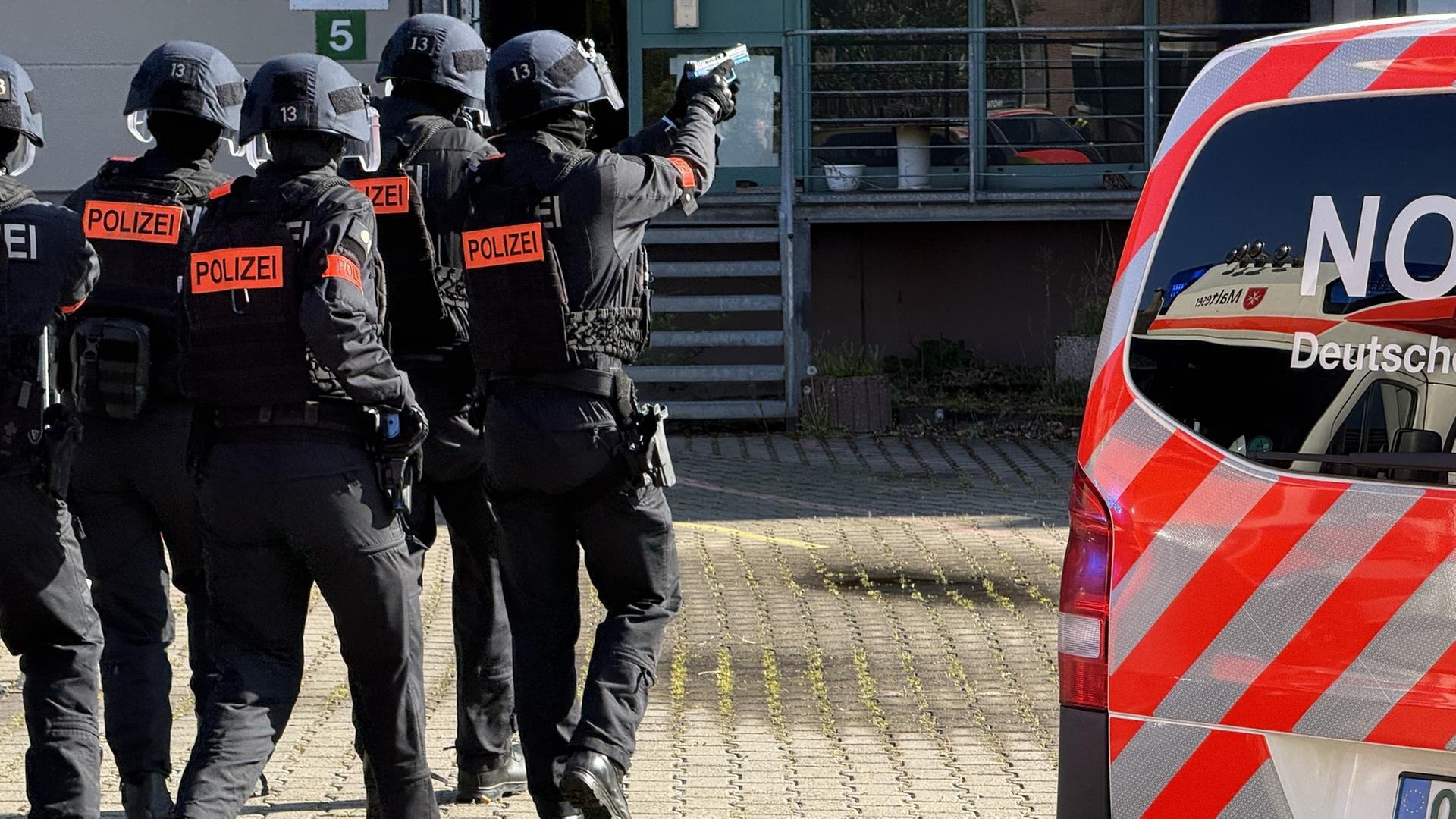 Polizisten laufen mit gezogener Waffe auf ein Gebäude zu. | NDR