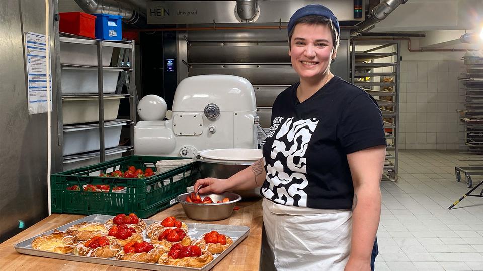 Bäckerin Jana Klausberger wandelte ihren Familienbetrieb in eine Genossenschaft um. | Inessa Baur Eine Frau arbeitet in der Bäckerei und lächelt in die Kamera.