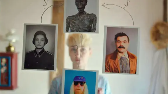 Auf einem Spiegel, in dem sich eine junge Frau spiegelt, sind vier Fotos geklebt.