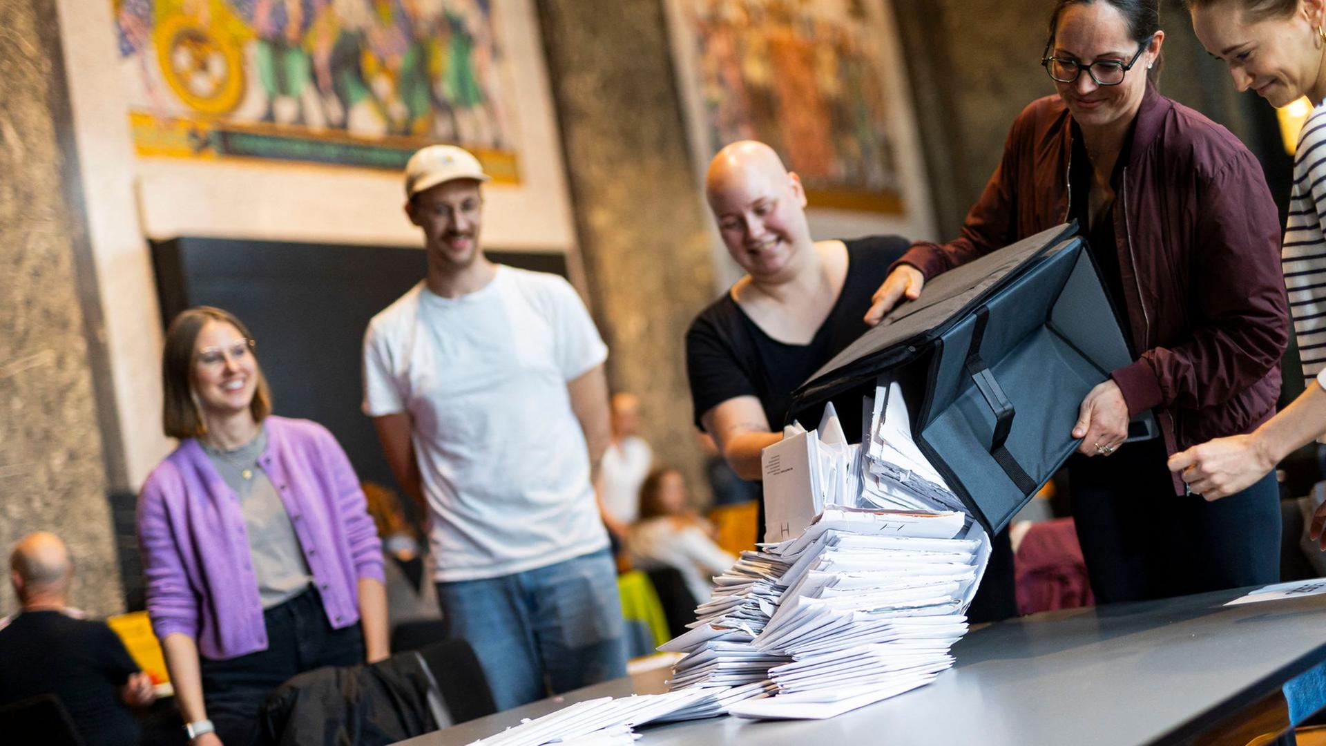 Wahlhelfer schütten Briefwahlunterlagen zur Auszählung auf einen Tisch im Neuen Rathaus aus. | dpa, Michael Matthey