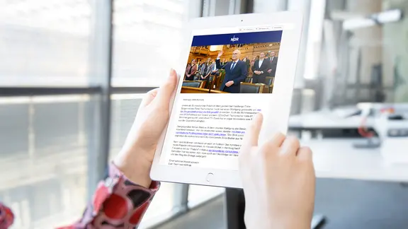 Eine junge Frau hält ein Tablett-PC auf dem man den NDR-Info Newsletter sieht.