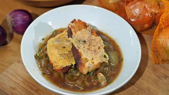 Zwiebelsuppe mit Käse-Croûtons in einem tiefen Teller serviert.